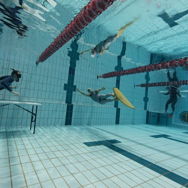 Freediver with monofin turns at the pool wall.